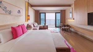 Crowne Plaza Ningbo Xiangshan Sea View, an IHG Hotel في Xiangshan: غرفة في الفندق مع سرير أبيض كبير مع وسائد وردية