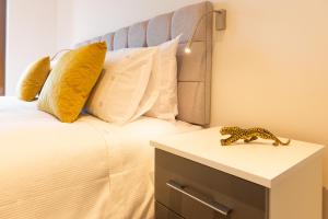 a bed with pillows and a leopard toy on a night stand at Beautiful 1 Bed Apartment in Centre of St Albans - Free Parking - 5 min walk to St Albans city centre & Railway station, 15mins drive to Harry Potter World - Free Super-fast Wifi in Saint Albans