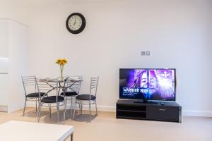 a living room with a tv and a table with chairs at Beautiful 1 Bed Apartment in Centre of St Albans - Free Parking - 5 min walk to St Albans city centre & Railway station, 15mins drive to Harry Potter World - Free Super-fast Wifi in Saint Albans