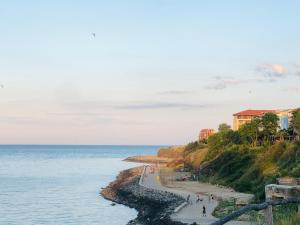 a group of people walking on a beach next to the ocean at Hotel Nikola in Primorsko