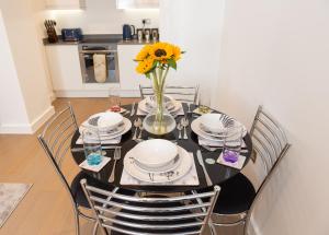 a dining room table with a vase with a sunflower on it at Beautiful 1 Bed Apartment in Centre of St Albans - Free Parking - 5 min walk to St Albans city centre & Railway station, 15mins drive to Harry Potter World - Free Super-fast Wifi in Saint Albans