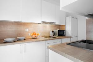a kitchen with white cabinets and a bowl of oranges at Elite Apartments Gospody in Gdańsk