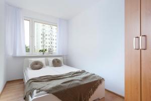 a white bedroom with a bed and a window at Elite Apartments Gospody in Gdańsk