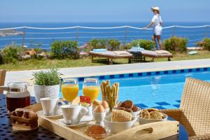 a table with breakfast food and drinks next to a swimming pool at Okeanides Villas in Bali