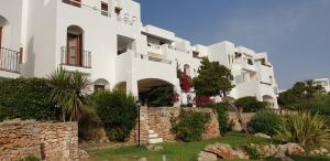 biały budynek apartamentowy z kamienną ścianą w obiekcie APARTMENT MARINA CALADOR HARBOURVIEW AIR CONDITION POOL GARDEN TERRASSE PORTO CARI spectacular location w mieście Cala d´Or