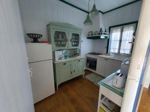 a kitchen with green cabinets and a white refrigerator at Palheiro Costa Nova in Costa Nova