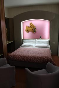 1 dormitorio con 1 cama con pared de color rosa en Hotel Costellazioni, en Troina