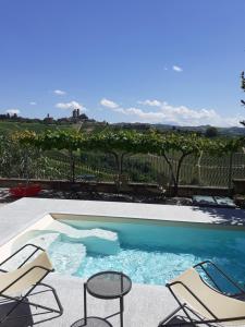 ein Schwimmbecken mit zwei Stühlen und einem Tisch in der Unterkunft Agriturismo I Grappoli in Serralunga d'Alba