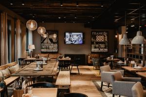 a restaurant with tables and chairs and a tv at Arivo Forchheim in Forchheim