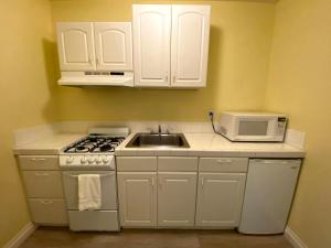 a kitchen with white cabinets and a sink and a microwave at Hollywood Celebrity Hotel in Los Angeles