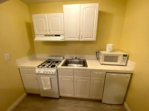 a kitchen with white cabinets and a sink and a microwave at Hollywood Celebrity Hotel in Los Angeles