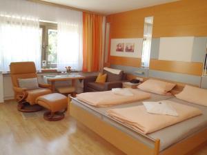 1 dormitorio con 2 camas, silla y sofá en Pension / FW Gästehaus Stern, en Bodenmais