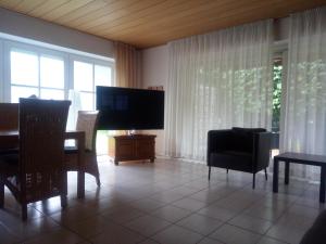 - un salon avec une télévision, une table et des chaises dans l'établissement Apartment am Vechtesee, à Schüttorf