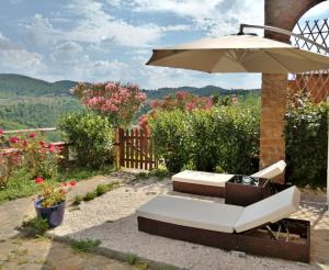 eine Terrasse mit einem weißen Sofa und einem Sonnenschirm in der Unterkunft LA ROSA DEI VESPUCCI Historic Apartments in Greve in Chianti