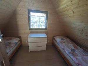 2 łóżka w drewnianym pokoju z oknem w obiekcie Agroturystyka i Domki Zacisze w mieście Jarosławiec
