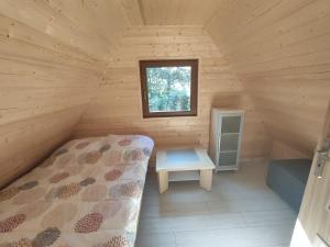a bedroom in a log cabin with a bed and a window at Agroturystyka i Domki Zacisze in Jarosławiec