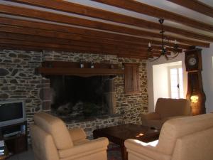 sala de estar con chimenea de piedra con 2 sillas y mesa en La Robinière, en Cerisy-la-Salle