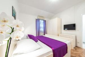 a bedroom with a white bed with purple sheets at Villa Mare & Filip in Zaton