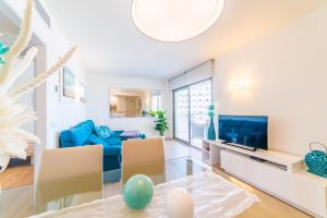 ein Wohnzimmer mit einem blauen Sofa und einem TV in der Unterkunft Sa Maniga 3E in Cala Millor