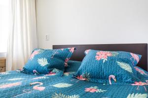 a bed with two blue pillows with flamingos on it at Aan Zee in Bergen aan Zee