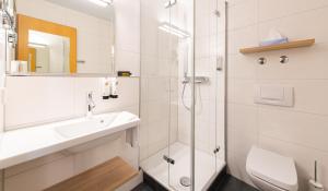 een witte badkamer met een wastafel en een douche bij ARAMIS Tagungs- und Sporthotel in Gäufelden