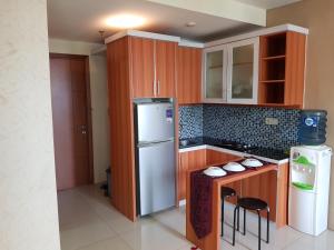 ジャカルタにあるwoodland park kalibata residence by Sang Livingの木製のキャビネットと白い冷蔵庫を備えたキッチン