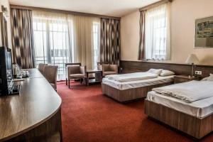 Cette chambre comprend deux lits et un bureau. dans l'établissement Hotel Három Gúnár, à Kecskemét