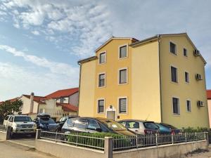 un edificio amarillo con coches estacionados frente a él en Apartments Marina, en Vodice