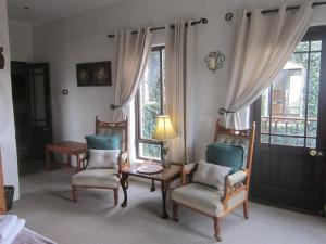 a living room with chairs and a table and windows at Dio Dell Amore Guest House in Jeffreys Bay