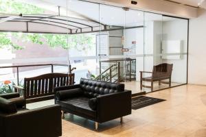 uma sala de estar com um sofá de couro e paredes de vidro em Central City Exclusive Apartments em Perth
