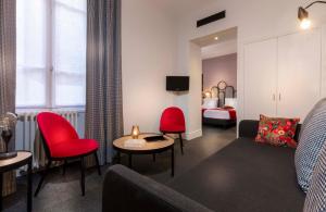 een hotelkamer met een bank en rode stoelen bij Hotel Saint Regis in Chalon-sur-Saône