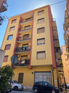 un edificio amarillo con coches estacionados frente a él en Five Rooms Brolo en Brolo