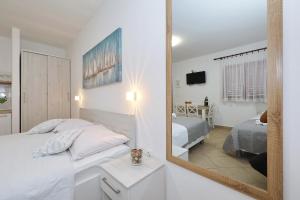 een hotelkamer met een spiegel en een bed bij Apartmani Strpić in Biograd na Moru