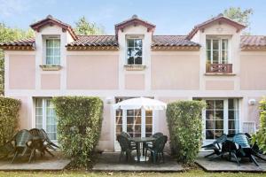 une maison rose avec une table et des chaises devant elle dans l'établissement Residence du Lac,Apt 2P, 5 pers,Monflanquin, à Monflanquin