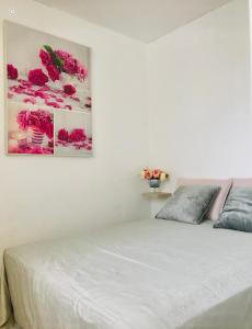 una camera da letto con un letto bianco e fiori rosa sul muro di L'ECRIN - Proche de RENNES - Lumineux - Au Calme a Liffré