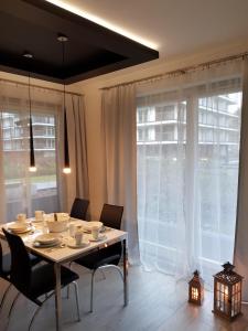 a dining room table with chairs and a large window at Family Apartment Golden Tulip 2 in Międzyzdroje