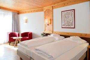two beds in a hotel room with red chairs at Hotel Burgstall in Neustift im Stubaital