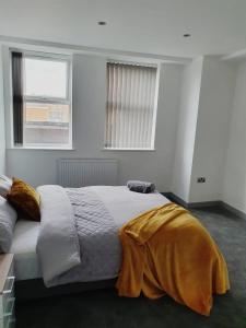 a bedroom with a large bed in a room with two windows at Cosy Executive City Apartment in Doncaster