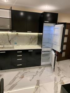 an empty kitchen with black cabinets and a refrigerator at Патилови in Sandanski