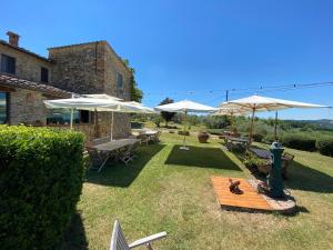 un patio con sombrillas, mesa y sillas en Agriturismo Macinello en Montefiridolfi