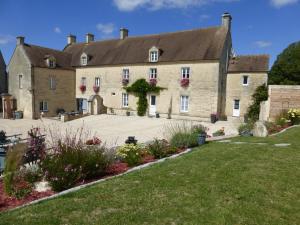 - un grand bâtiment en pierre avec une pelouse devant dans l'établissement La Charretterie, à Martragny