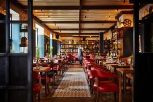 فندق ويست بورت بلازا، سبا ولايجر في ويستبورت: مطعم بطاولات وكراسي حمراء ورجل يمشي في الخلفية