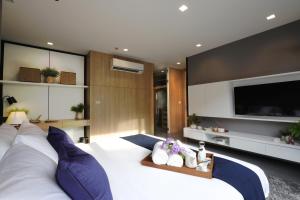 a bedroom with a large white bed and a flat screen tv at Alix Bangkok Hotel in Bangkok