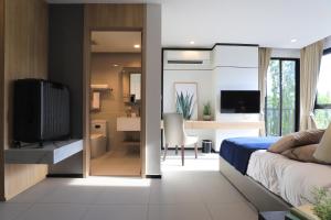 a bedroom with a bed and a television and a desk at Alix Bangkok Hotel in Bangkok