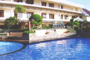 a hotel with a swimming pool in front of a building at Hotel Mutiara Baru in Batu