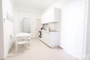 uma cozinha branca com uma mesa e um frigorífico branco em Casa Viviana - Bari Policlinico em Bari