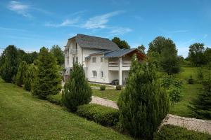 una gran casa blanca con un patio con árboles en Studio apartments Kaya en Čatrnja