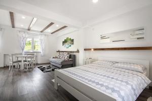 a white bedroom with a bed and a table at Studio apartments Kaya in Čatrnja