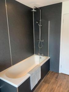 a bathroom with a bath tub with a shower at Town Centre Apartment in Hawick