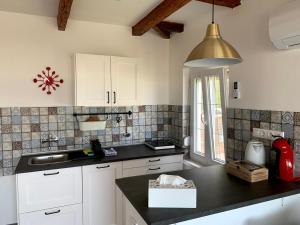 uma cozinha com armários brancos e um balcão preto em Exclusive Beachfront Villa em Fonyód